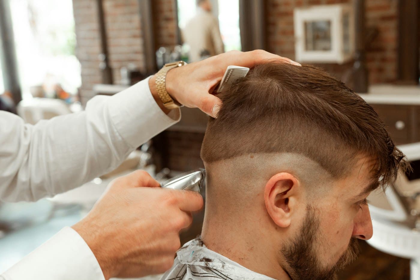 Barbero cortando el pelo a un cliente con máquina